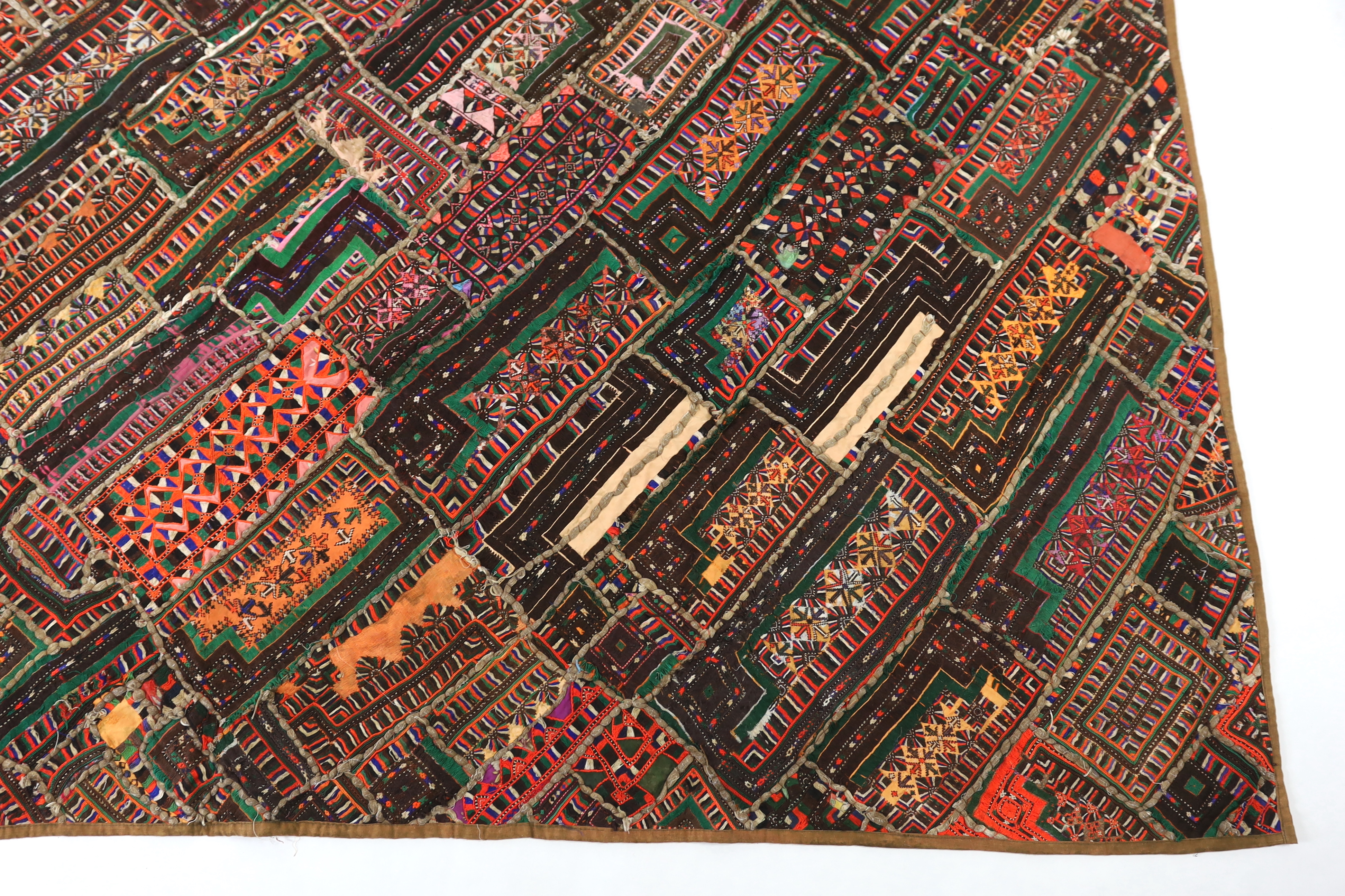 An interesting 20th century North Indian or Tibetan patchworked cover, worked in silk, wool and cotton embroidery in varying colours using thick bundles of threads to border / outline the patchwork, this has possibly bee